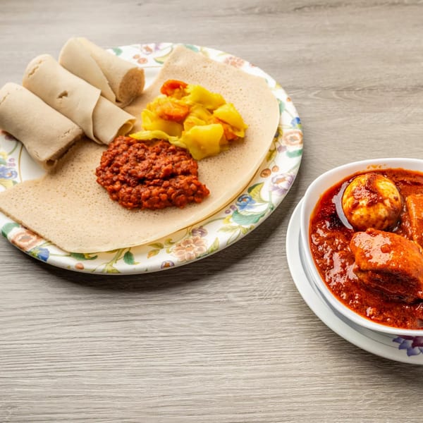Ethiopian injera bread with red lentil stew, yellow cabbage, and a bowl of Doro Wat.
