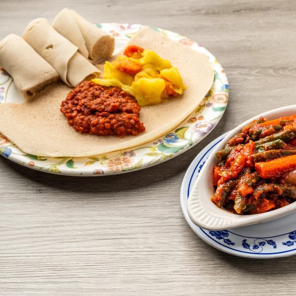 Ethiopian injera bread with red lentil stew, yellow cabbage, and a side of vegetable stew.